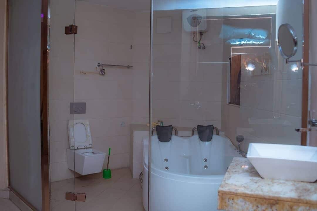 A modern bathroom with a glass shower enclosure, a white sink, and a toilet.