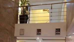 Eine geräumige Lobby mit Marmorboden, einer Treppe zu einer oberen Ebene und Zimmerpflanzen.