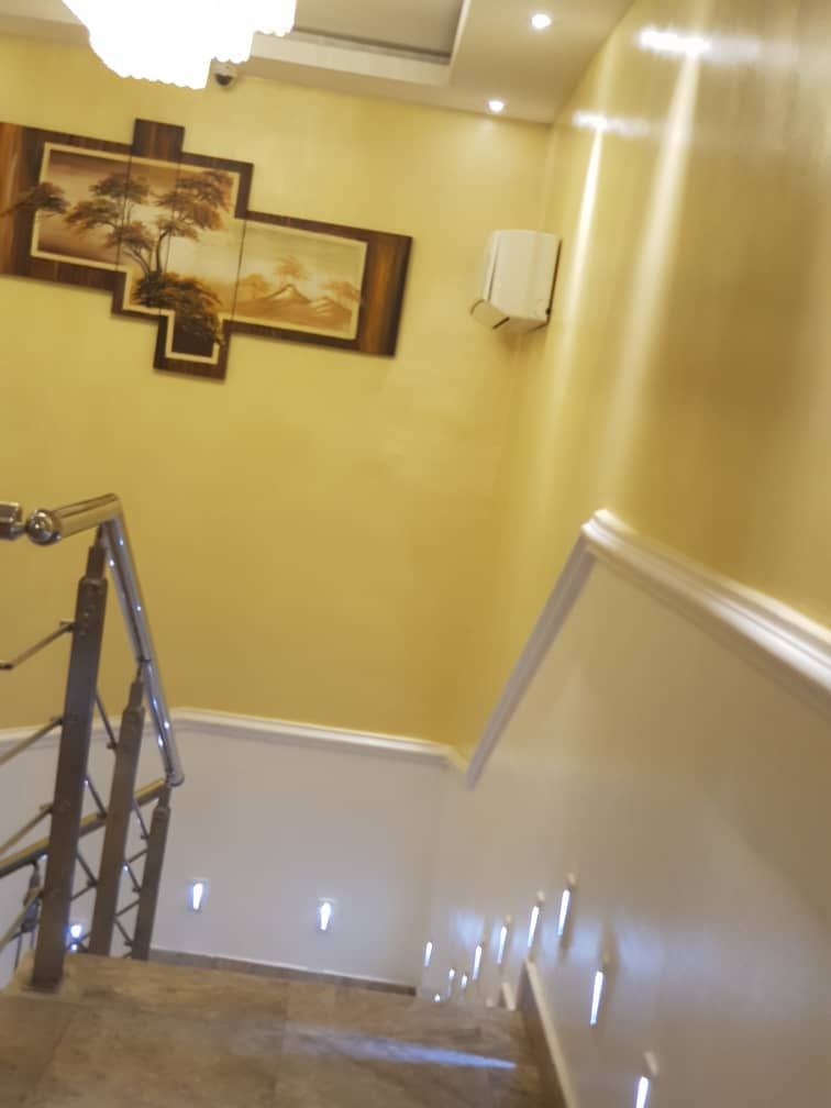 A staircase with a handrail, a wall-mounted light fixture, and a framed artwork.
