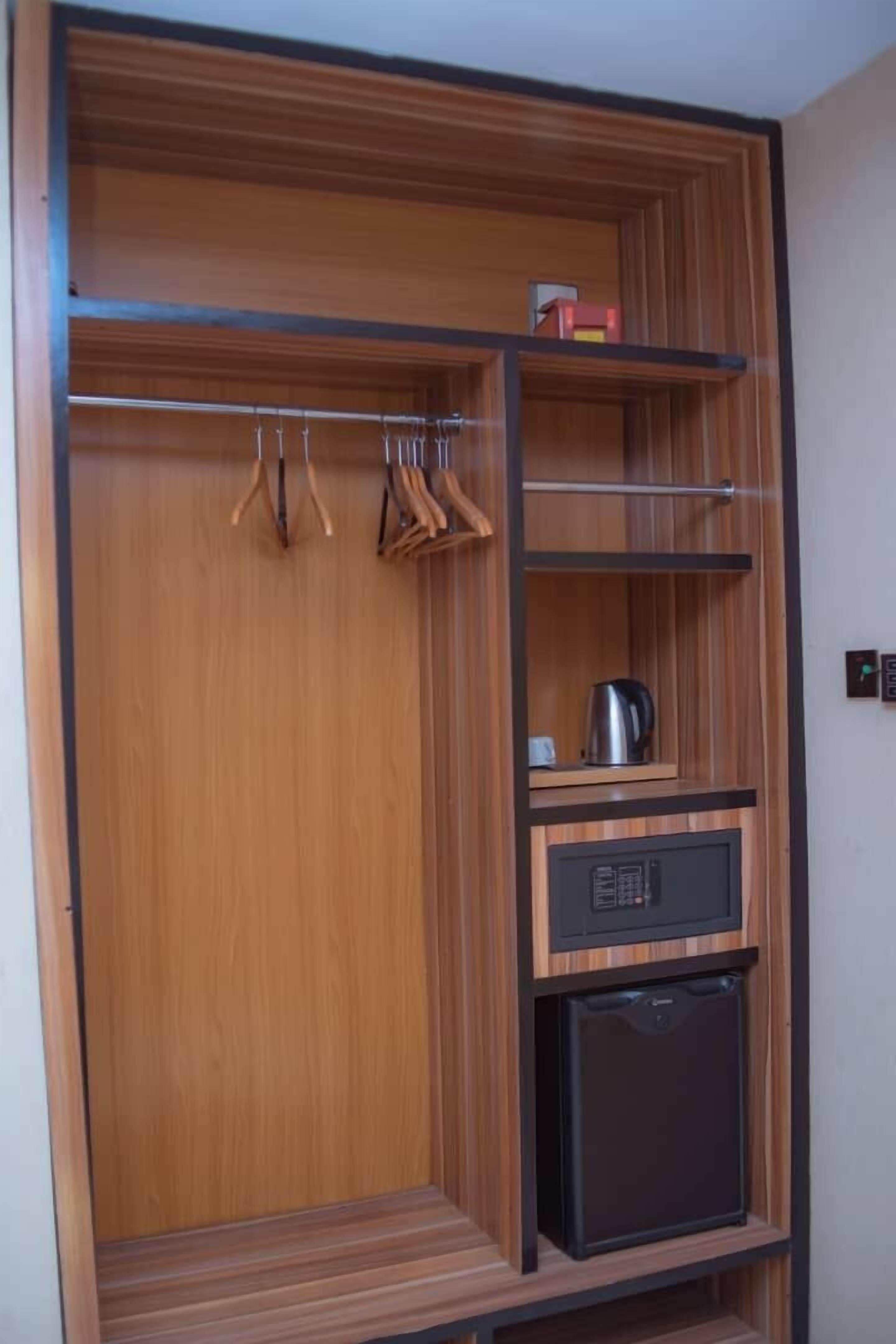 A wooden wardrobe with multiple shelves, a hanging rack, and a small appliance.