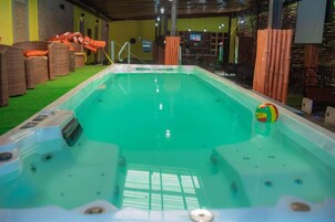 Una piscina con un jacuzzi, rodeada de muebles de mimbre y decoración de bambú.