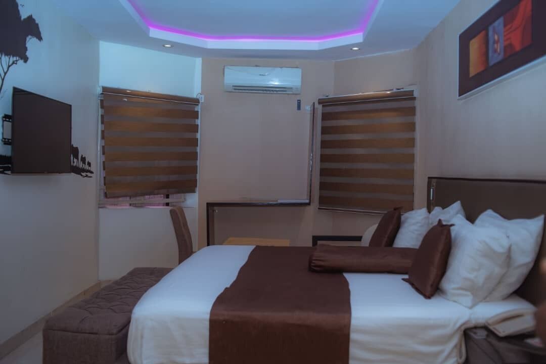 A hotel room with a bed, a desk, and a TV mounted on the wall.