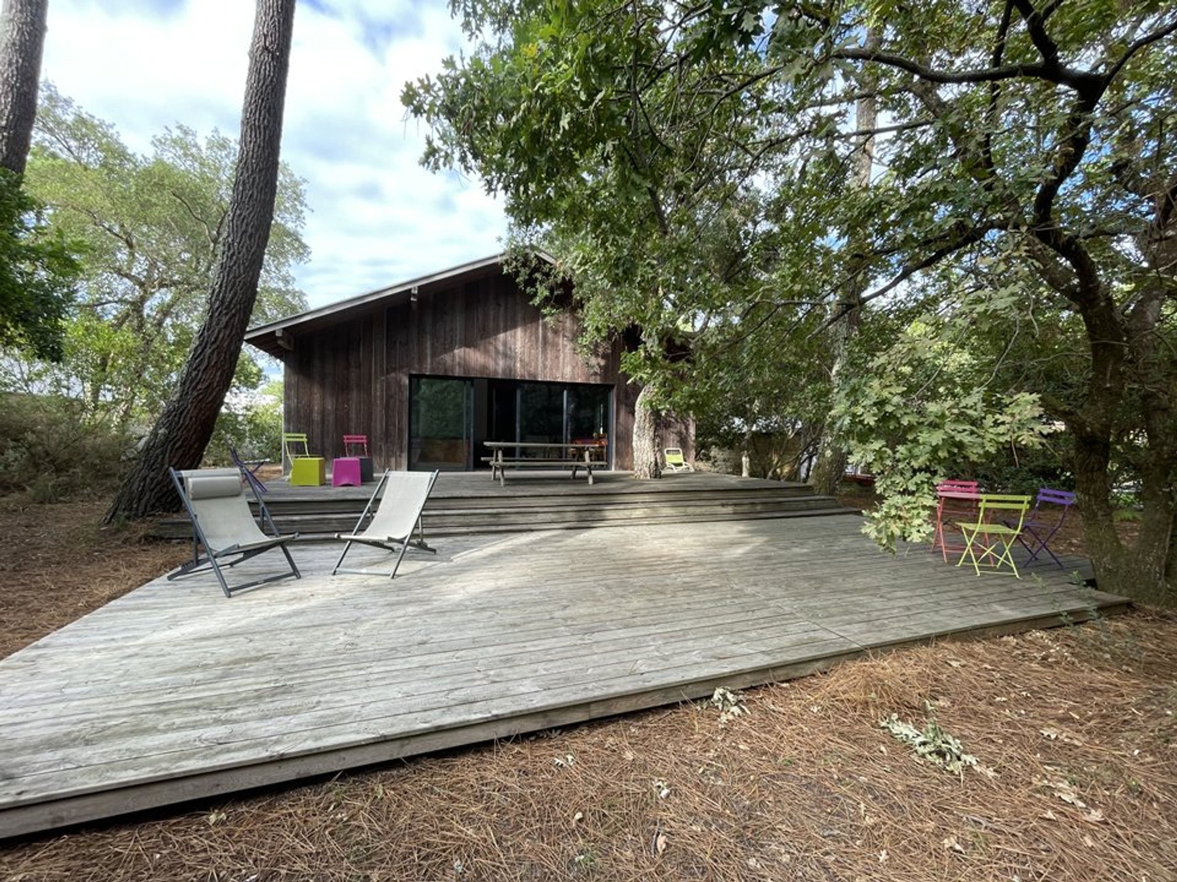 A wooden deck with outdoor seating and a building with large windows.