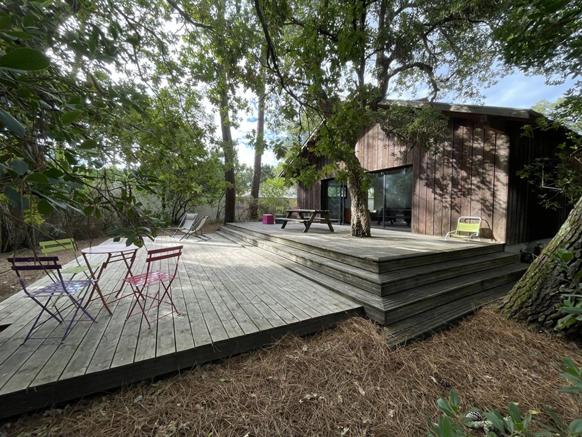 Une terrasse en bois avec des sièges d’extérieur et un bâtiment doté de grandes fenêtres.