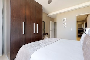 Un dormitorio con una cama grande, un armario de madera oscura y un baño visible a través de una puerta abierta.