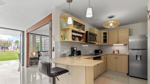 Una cocina moderna con una isla central, electrodomésticos de acero inoxidable y armarios de madera.