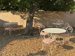 An outdoor seating area with metal tables and chairs, surrounded by a gravel ground and a tree. - Hôtel Charles (Les Arcs-sur-Argens)
