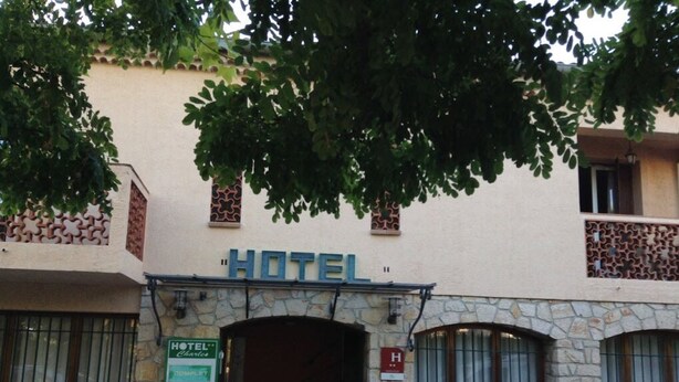 A hotel entrance with a stone facade, a sign reading "HOTEL", and a green sign indicating "HOTEL Charcas". - Hôtel Charles (Les Arcs-sur-Argens)