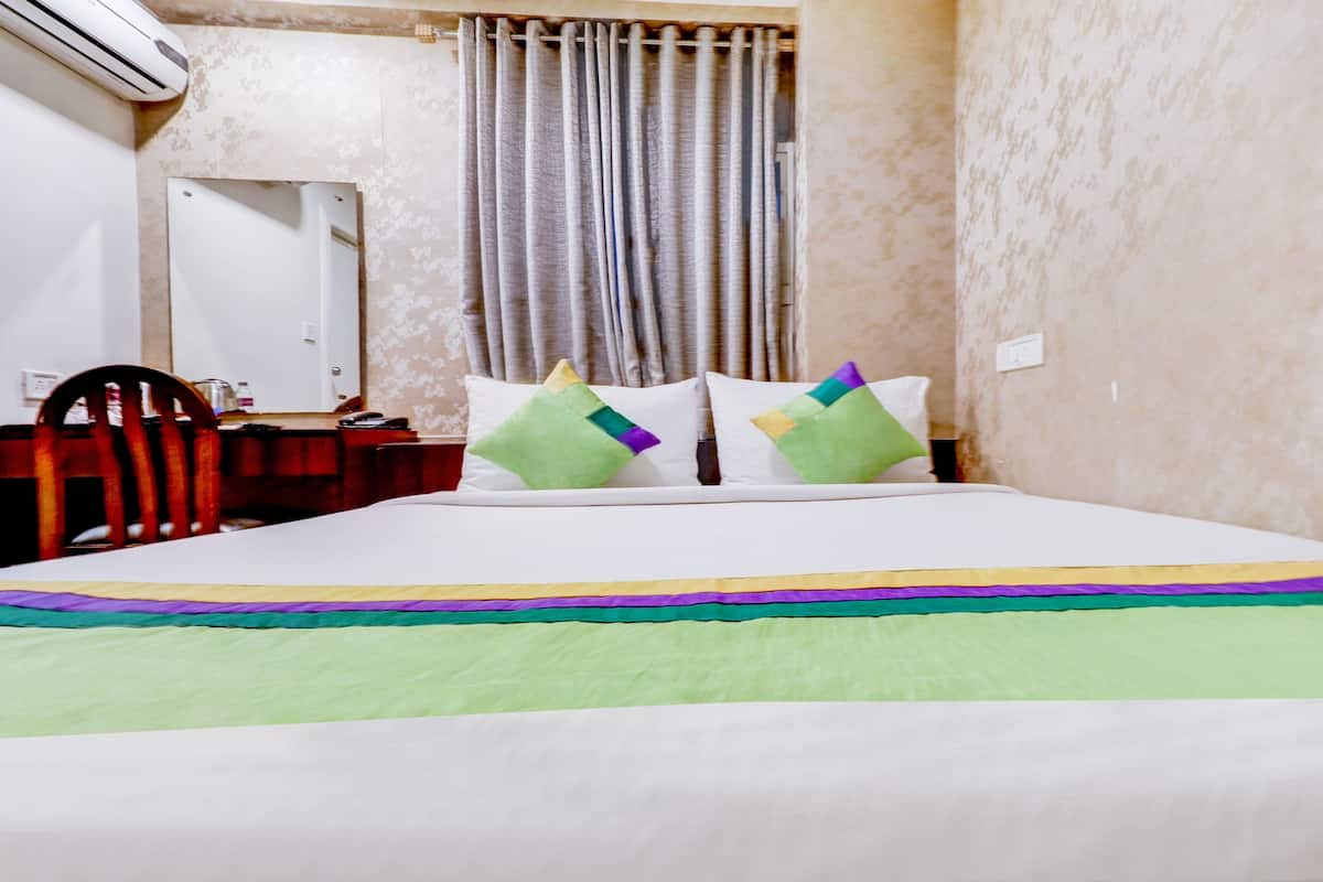Ein Hotelzimmer mit einem Bett, einem Holzstuhl, einem Schreibtisch und einem Spiegel.
