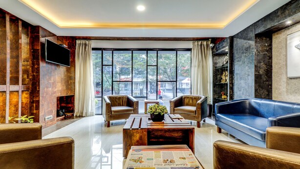 Una sala de estar moderna con sofás de cuero, una mesa de centro y una chimenea. Amplias ventanas ofrecen vistas a la ciudad.