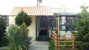 A house with a red and white striped awning, a wooden fence, and a small porch.