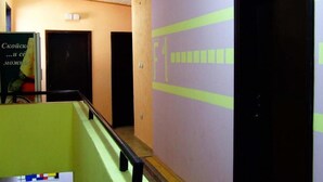 A hallway with a purple wall, a green bench, and a door with a yellow stripe.
