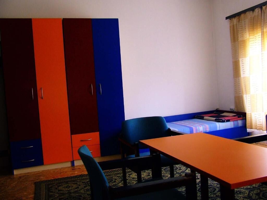 Ein Zimmer mit einem Bett, einem Tisch, einem Stuhl und einem Kleiderschrank.