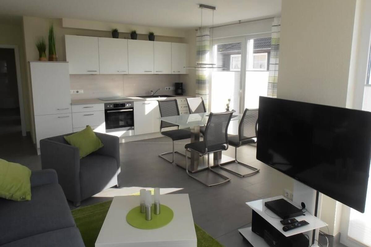 A modern living room with a grey sofa, a coffee table, and a flat-screen TV.