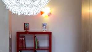A red bookshelf with books and framed pictures, a white decorative light fixture, and a wooden wardrobe. - Villa Pandora - Angela & Michali (Platanias)