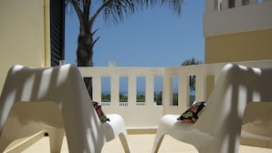 Two white plastic chairs with colorful cushions on a balcony with a view of the sea and palm trees. - Villa Pandora - Angela & Michali (Platanias)