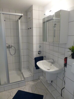 A bathroom with a shower, sink, and mirror.