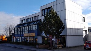 A modern building with large windows and a sign indicating it is a government office. - Atelier Guesthouse (Filderstadt)