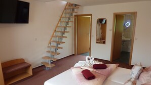 A hotel room with a bed, a staircase, a TV, and a bathroom visible through an open door. - Spreewald Pension Spreeaue (Burg (Spreewald))