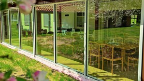 A modern house with large sliding glass doors, a patio with outdoor furniture, and a garden. - Spreewald Pension Spreeaue (Burg (Spreewald))