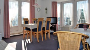 Ein Essbereich mit Tisch, Stühlen, Fernseher und Heizkörper.