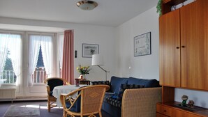 Ein Wohnzimmer mit Sofa, Sessel, Tisch und Schrank.