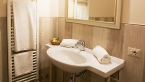 Ein Badezimmer mit einem weißen Waschbecken, einem Spiegel und einem Handtuchhalter mit mehreren Handtüchern.