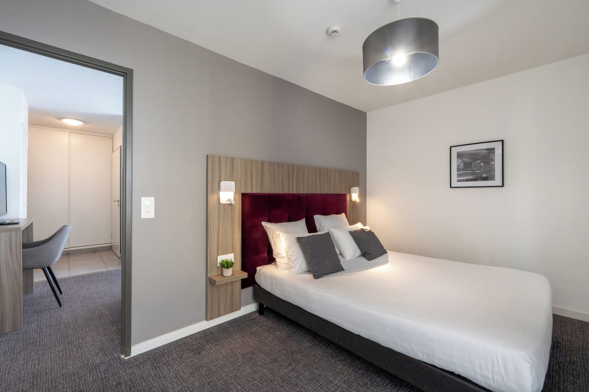 Ein modernes Hotelzimmer mit einem großen Bett, einem Schreibtisch und einem Sessel.