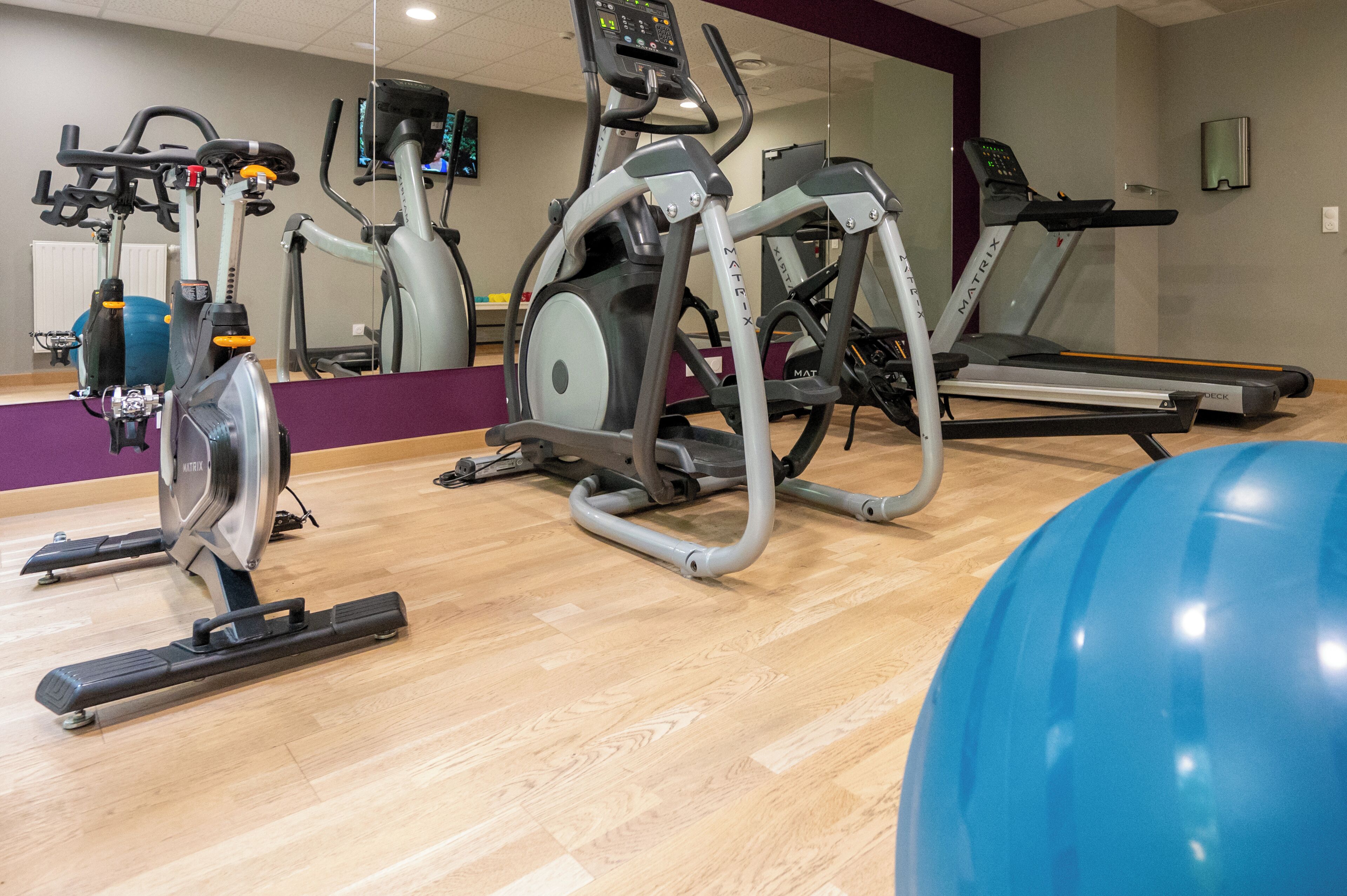 A gym with various exercise equipment including treadmills, an elliptical, and a stationary bike.