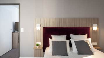 Habitación de hotel con una cama grande, dos mesitas de noche, un televisor y un cabecero de madera.