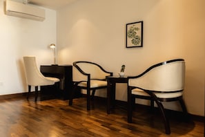 A small, cozy room with two chairs, a small table, and a single potted plant.