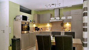 Eine moderne Küche mit Essbereich, ausgestattet mit Edelstahlgeräten, einem eingebauten Backofen und einem Esstisch mit Stühlen.