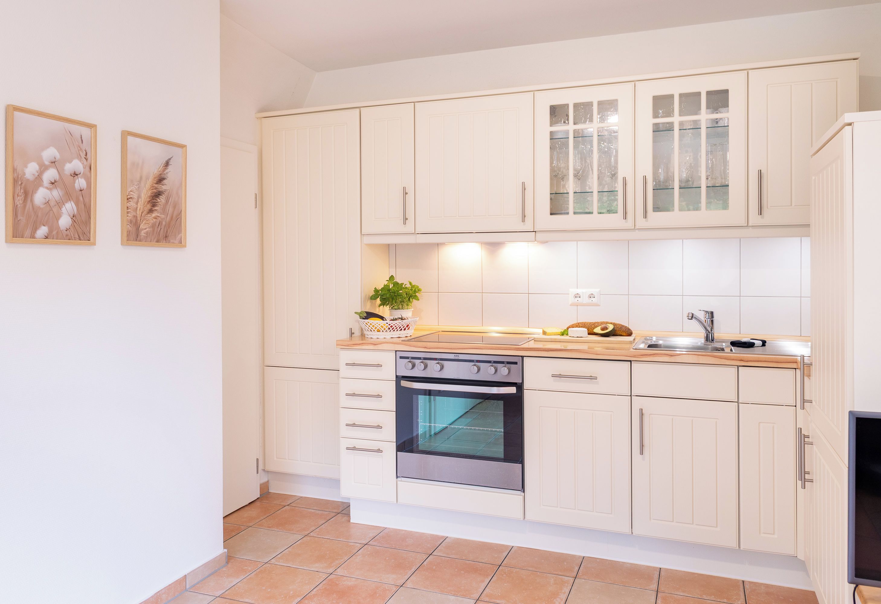A kitchen with white cabinets, a built-in oven, a sink, and a countertop with various items.