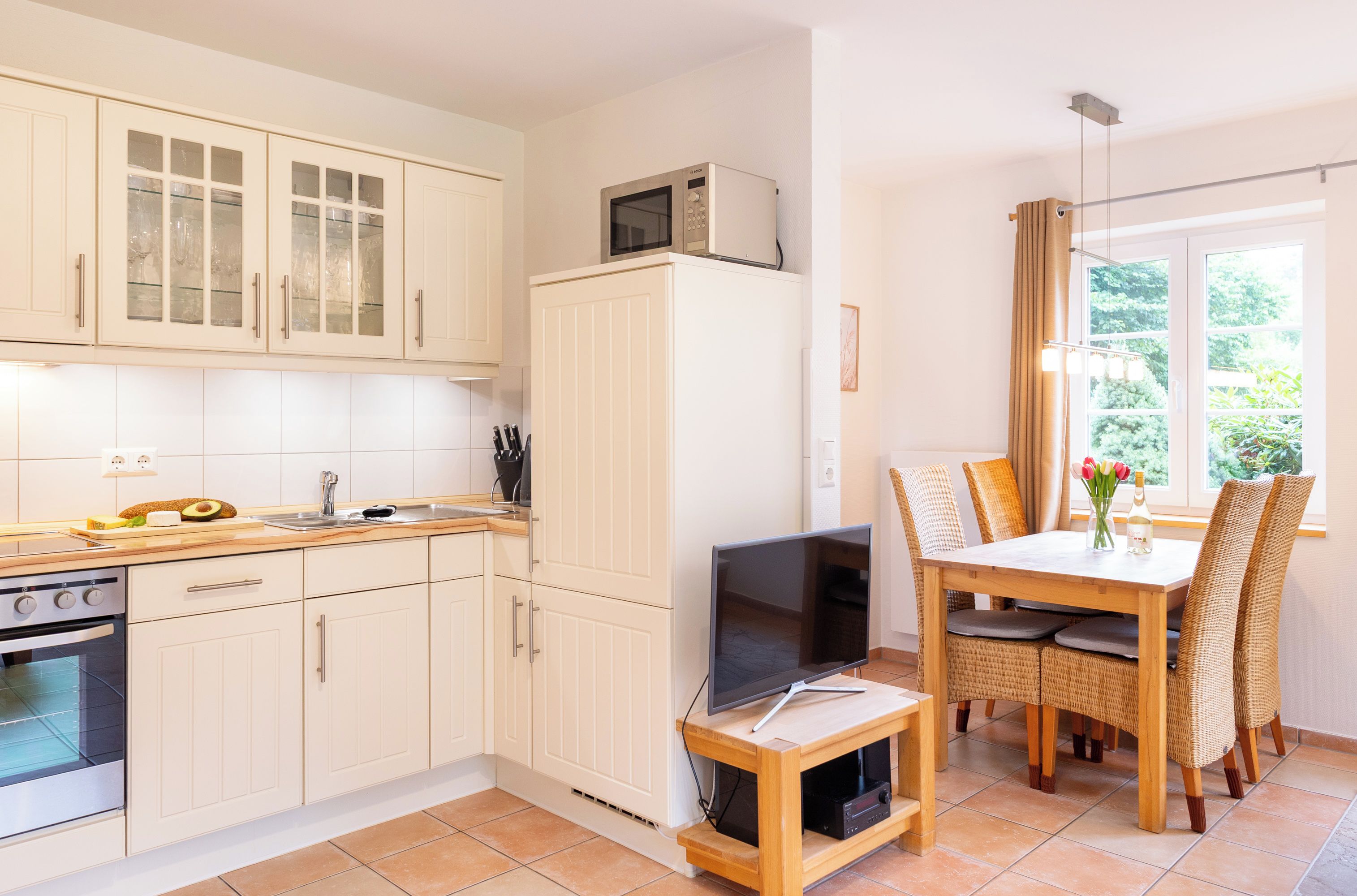 A compact kitchen with a microwave, oven, and dining area with a TV.