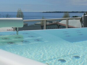 Piscina azul cristalina con jacuzzis, rodeada por un balcón con vistas al mar.