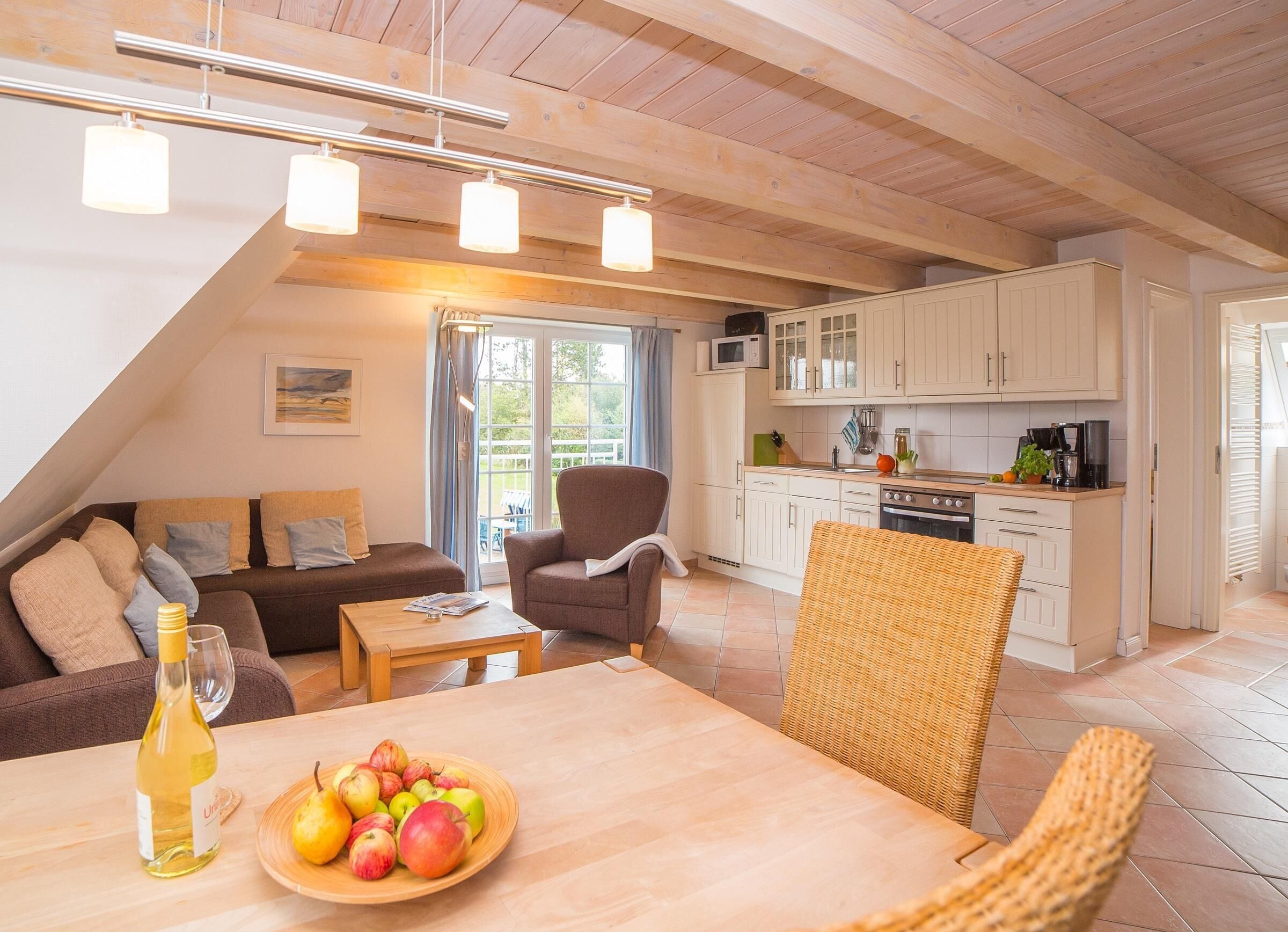 Una sala de estar acogedora con un sofá, una mesa de comedor con fruta y una cocina con armarios blancos y una estufa.