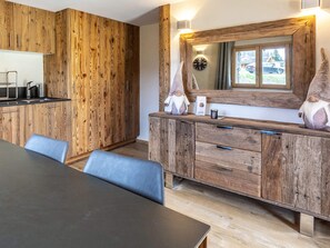 A modern kitchen with wooden cabinetry, a dining table, and a large mirror above the counter.
