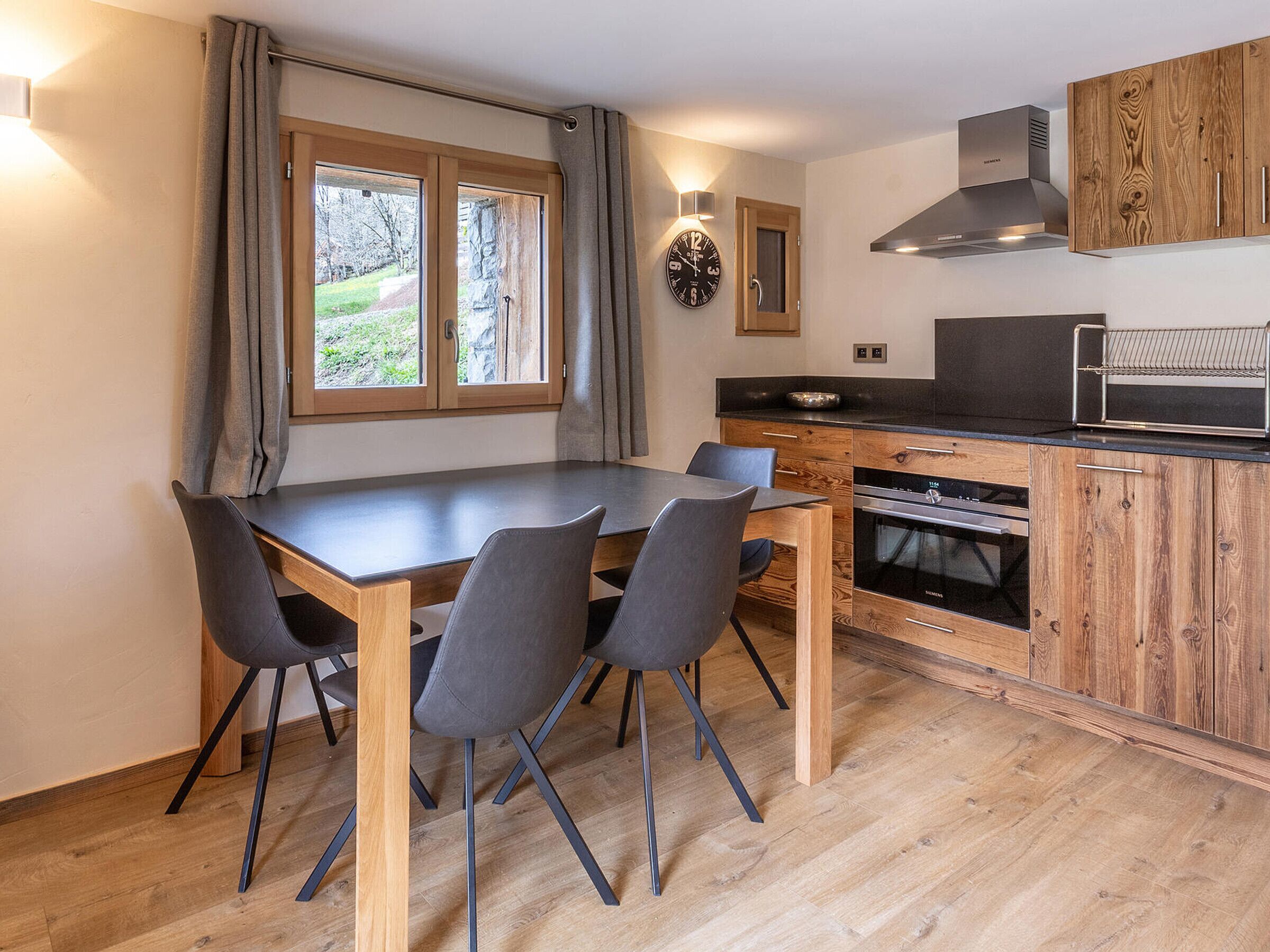 Eine moderne Küche mit Holzausstattung, integriertem Backofen und einem Essbereich mit Tisch und Stühlen.