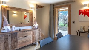A modern room with a wooden vanity, a large mirror, and a dining table with chairs. - Cozy Chalet - 1 BR - 4 Pers - Terrace - Parking (La Clusaz)