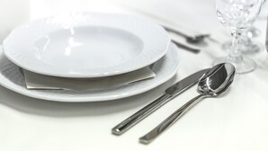 A neatly arranged dining table with a plate, a spoon, and a knife.