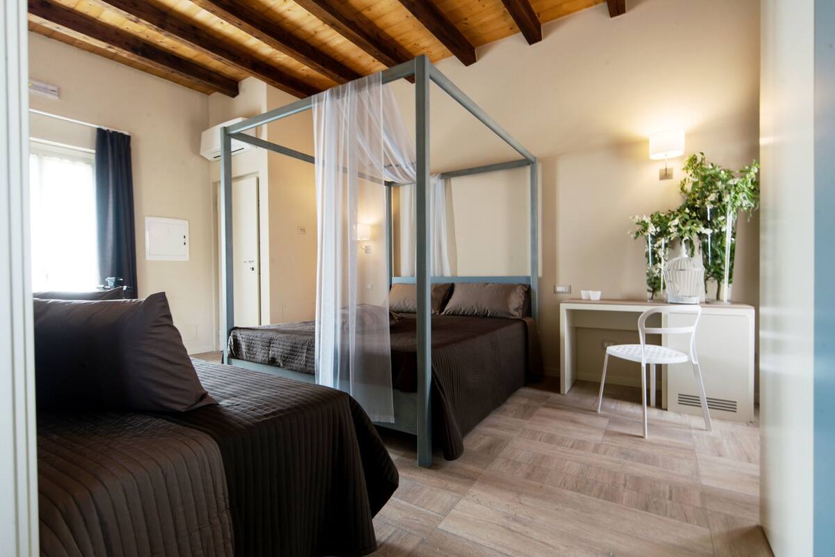 A bedroom with two beds, a desk, and a chair.
