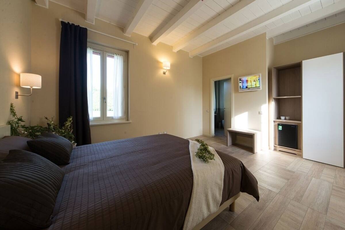A bedroom with a bed, a TV, a wardrobe, and a small desk.