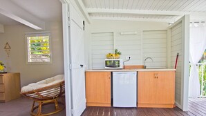 A compact kitchen with wooden cabinets, a microwave, and a small refrigerator.