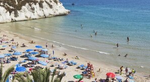 A beach with sun loungers and umbrellas, a lifeguard tower, and clear blue water. - Mayna (Benidorm)