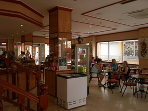 A restaurant with a wooden staircase, tables, chairs, and a refrigerator with beverages. - Mayna (Benidorm)