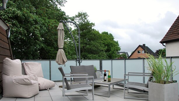 An outdoor patio with seating, a table, and a potted plant.