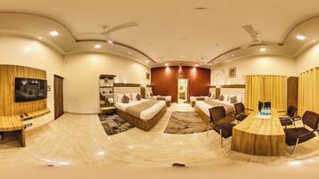 Una habitación de hotel amplia con una cama grande, televisión, zona de estar y mesa de comedor.