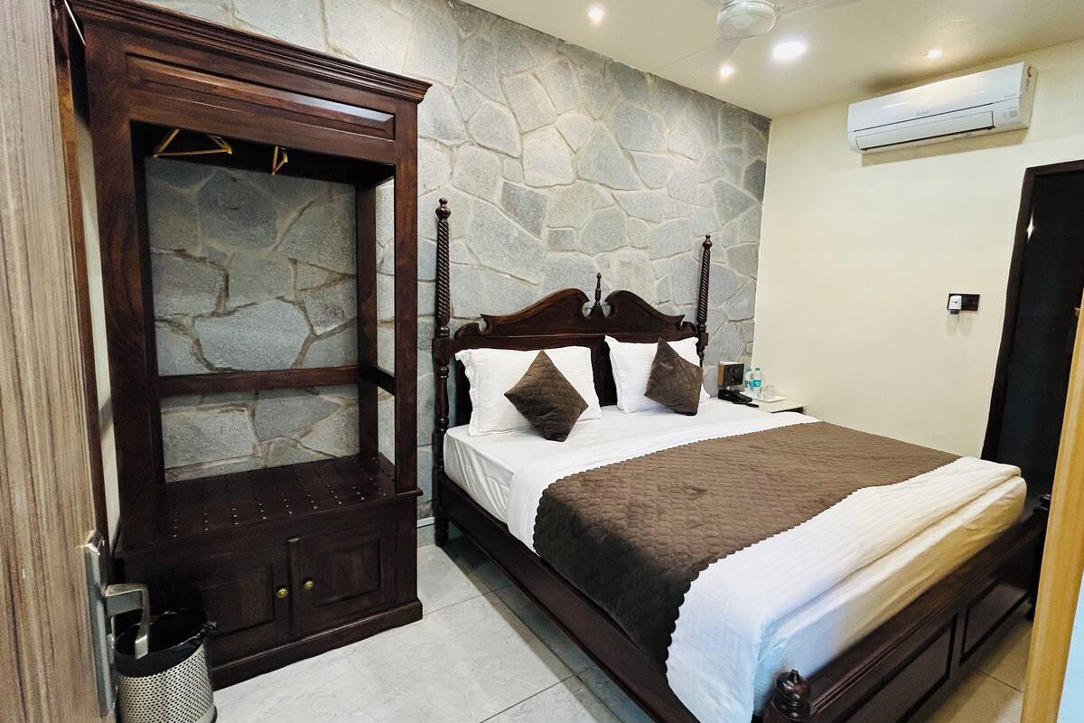 A bedroom with a stone wall, a wooden bed frame, and a built-in wardrobe.