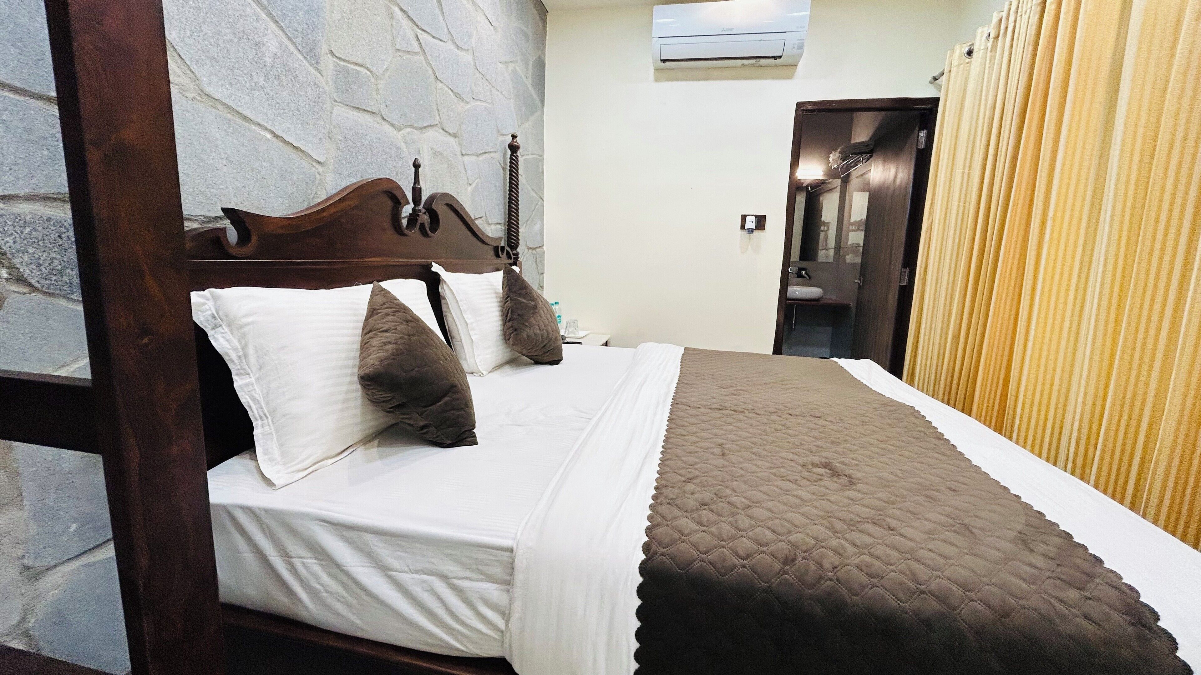 A neatly made bed with a wooden headboard, white and brown bedding, and a quilted blanket.