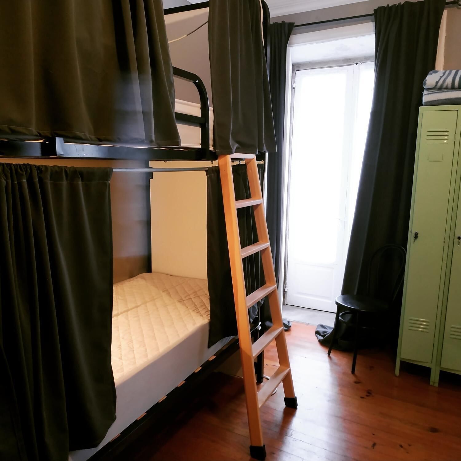 Una cama litera con escalera de madera, un escritorio y un armario en una habitación con puerta corredera.